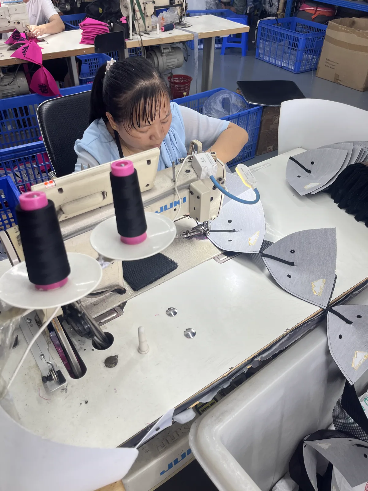 Hat panels being stitched on an industrial sewing machine at the SXMX factory